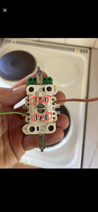 Elektrisk kopplingsplatta med inringade skruvar där en mejsel kan användas för trycktest.