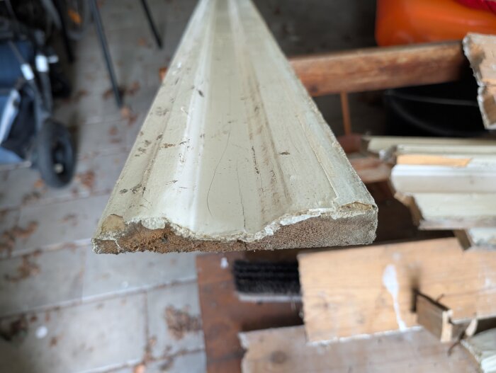 Träbit med avskavd färg i närbild på ett arbetsbord i ett garage.