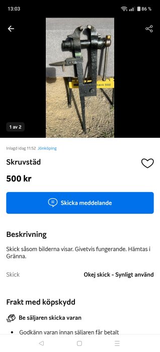 Gammaldags skruvstäd i svart metall, monterat på en arbetsbänk, omgiven av grusig mark.