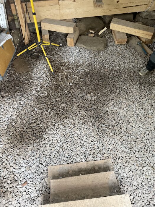 Grusbelagt utrymme med trästöd och belysningsstativ. Skiftningar i stenens mörker där lager är tunnare. Fotot taget i början av juni.