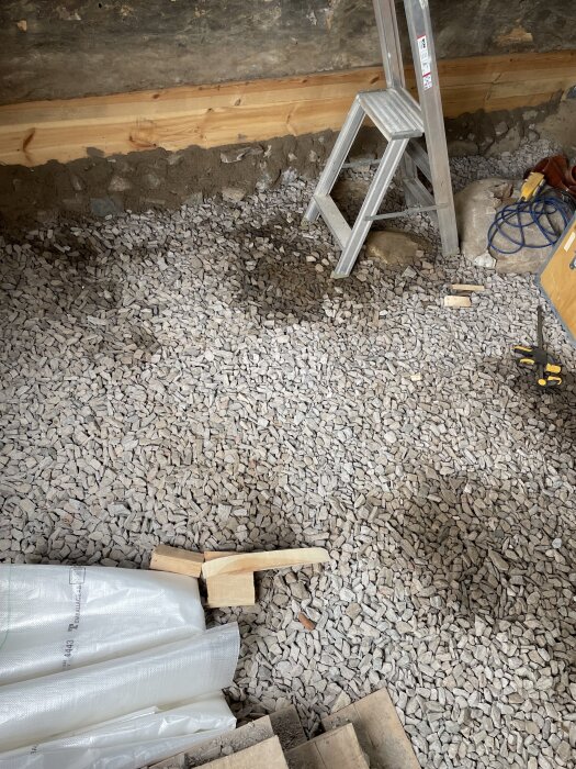 Stenbelagd golvsektion med stegstege, plastskiva och byggverktyg; bilden är från början av juni.