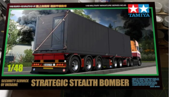 Förpackning av modelltruck med stora släpvagnar och texten "Strategic Stealth Bomber" från Tamiya, skala 1/48, med bakgrund av rök och träd.