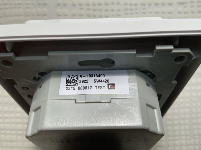 Termostatens baksida med synlig kopplingsplint och etikett med tekniska specifikationer.