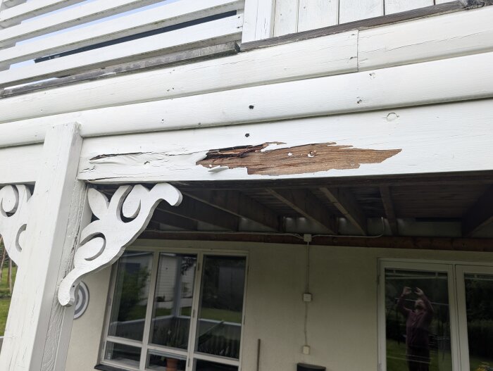 Rötangripen balk med skador, en extra balk bultad som förstärkning på ett hus. Dekorativ trädetalj synlig under balken.