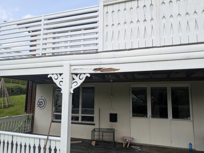 Balkong med rötskadat trä och bultad extra balk, del av husfasad och veranda, vitmålad trästruktur.