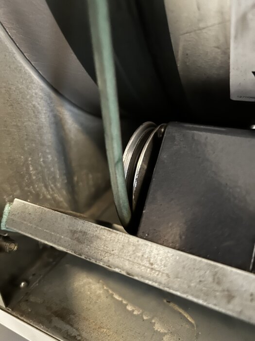 Närbild av en motor med ett tillhörande hjul och en rem. Hjulet snurrar inte när trumman snurras för hand.