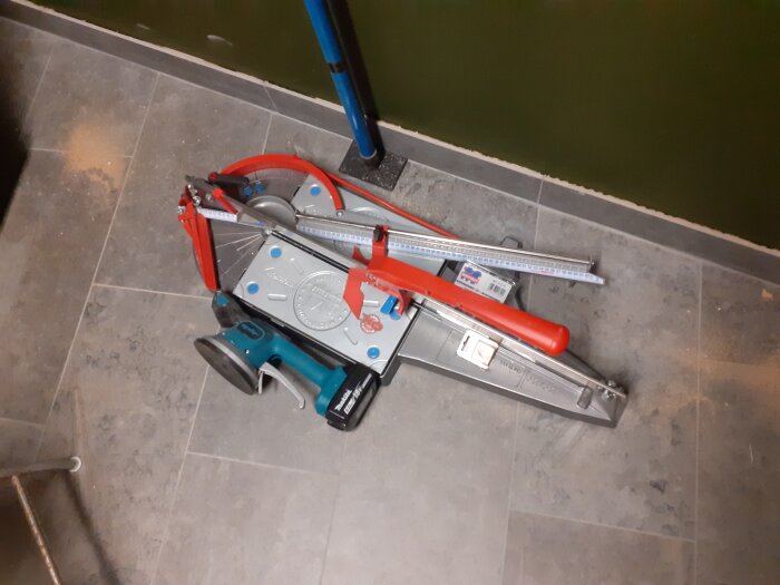 Kakelskärare och Makita-driven plattvibrator ligger på nylagt golv.