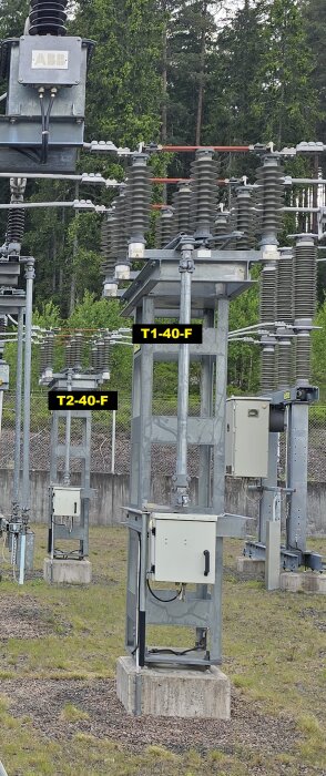 Utomhusanläggning med elektriska frånskiljare märkta T1-40-F och T2-40-F, placerade på betongfundament med omgivande vegetation.
