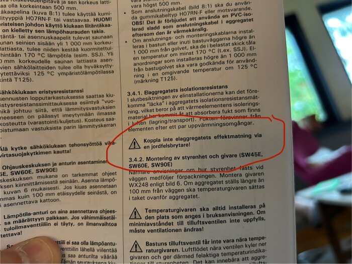 Närbild på en bruksanvisning för Harvia bastuaggregat med text som varnar för att koppla elaggregatets effektmatning via en jordfelsbrytare.