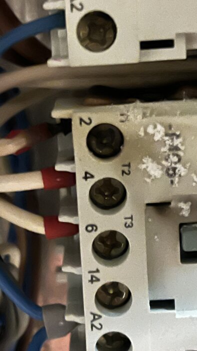 Elektrisk kopplingsplint med nummer och skruvanslutningar, omgivna av flera kablar.