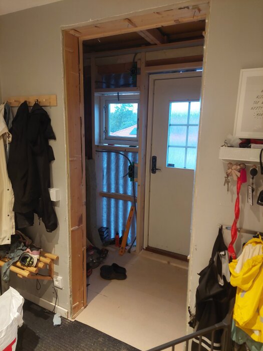 Ytterdörr och fönster installerade i en hall under renovering, med byggmaterial och verktyg synliga på golvet.