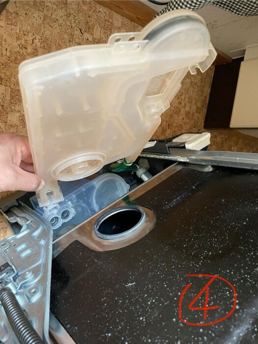 Vattentank från diskmaskin, borttagen och hålls av en hand, med nummer 4 markerat i rött.
