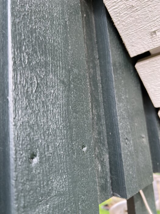 Grönmålad trävägg i närbild, mer skyddad och mindre sliten än andra delar av byggnaden.