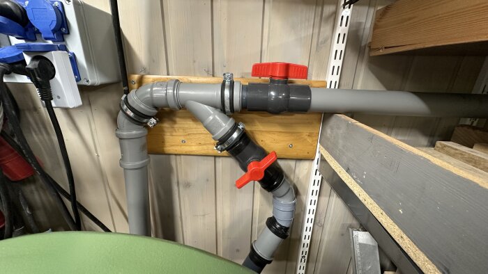 Två grå rörsystem med röda kulventiler monterade på en trävägg. Används för anslutning till en Dewalt cyklon och grovsug.