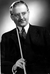 En man i kostym håller i en biljardkö, med glasögon och slips. Bilden är svartvit.