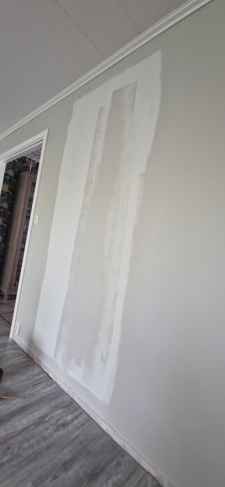 Grå væg med rektangulært område, der er spartlet, klar til gips eller fliser. Umtænkt montering eller opdatering af vægdesign.