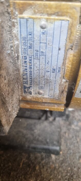 Guldfärgad motor med informationsskylt, märkt Hanning Elektro-Werke. Synliga tekniska specifikationer och serienummer. Lätt slitage och damm.