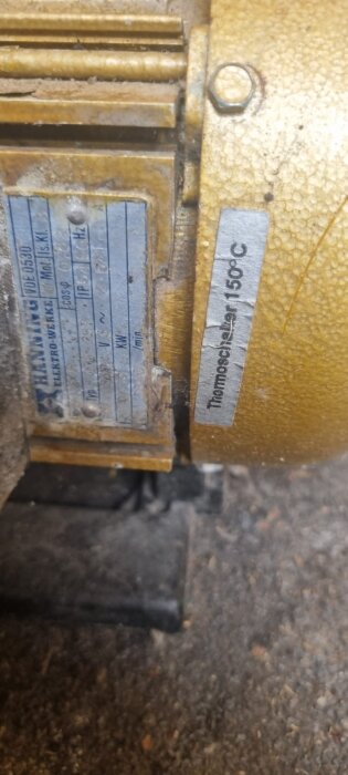 Guldfärgad motor med etikett som visar "Thermoschalter 150°C" och en sliten tillverkarplatta.