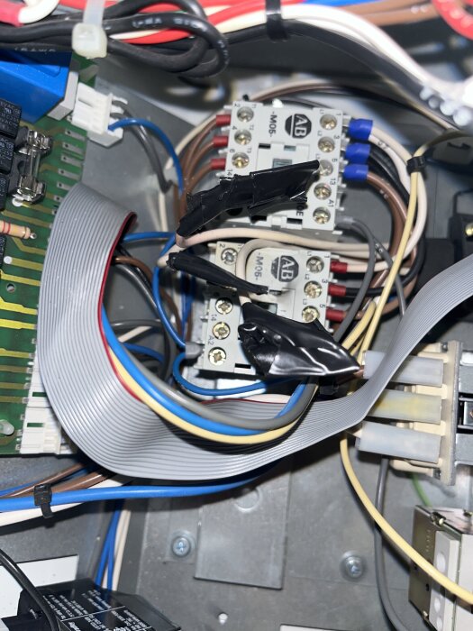 Elektrisk kopplingslåda med kablar anslutna till en kontaktor, några kablar säkrade med svart tejp.