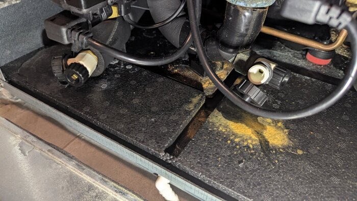 Närbild på två vita ventiler i ett rörsystem, omgivna av svarta slangar och anslutningar. Ventilerna är del av ett avluftningssystem.