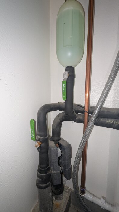 Rörsystem med gröna Altech-handtag och tryckkärl i hörn av rum.