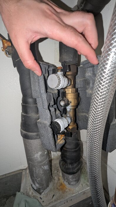 Värmerör med ventiler och isolering, en hand justerar komponenterna.