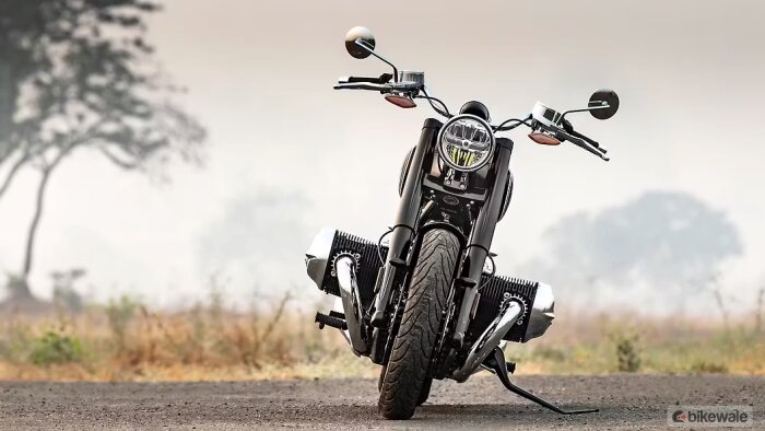 Motorcykel lutande på ett landsväg, färdig för provkörning mot en suddig bakgrund av träd och fält.