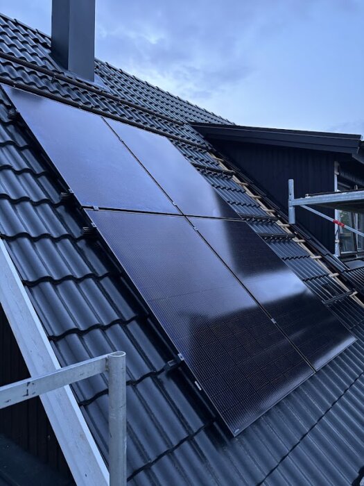 Solceller monterade på ett svart tegeltak med en påbörjad väggpanel på byggnadens kupa i bakgrunden.