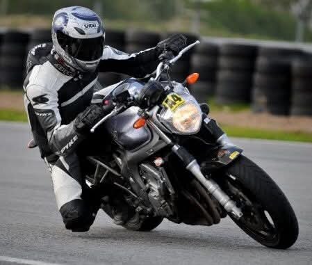 Motorcyklist i kurva på bana iförd svarta och vita skyddskläder.