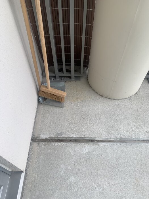 Balkonggolv med smutsfläckar, en kvast står lutad mot en vägg. Behöver hjälp med att identifiera och rengöra fläckarna.