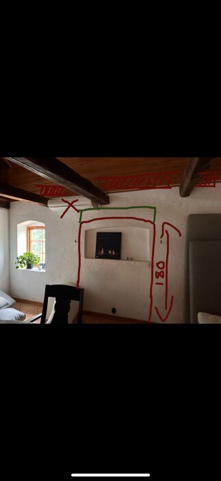 Inomhusbild av en vägg med ritad röd och grön markering för dörröppning. Synliga bjälkar i taket.