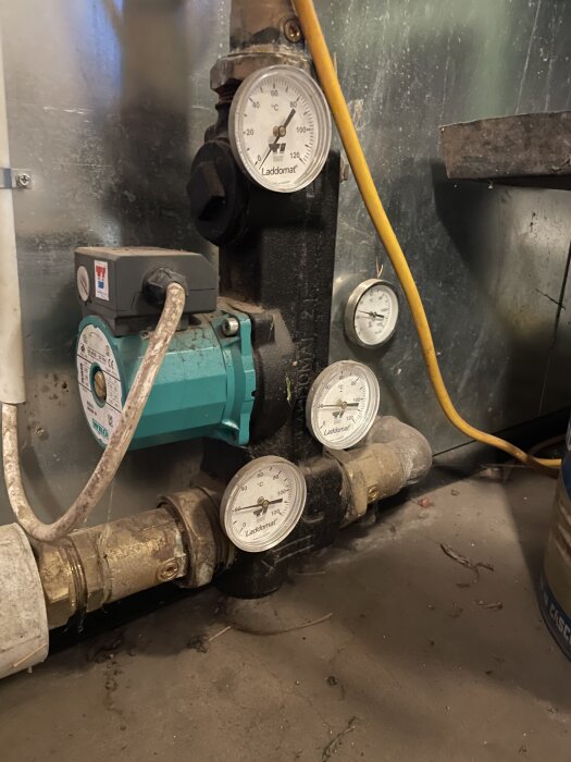 Laddomat-enhet med tre temperaturmätare och en cirkulationspump i ett fritidshus.