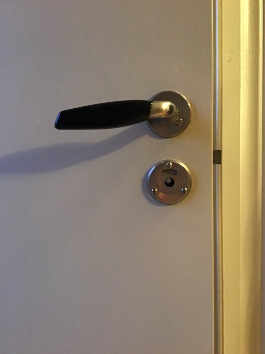 Dörrhandtag och lås på en dörr med saknad röd och grön indikator för låst eller olåst läge.
