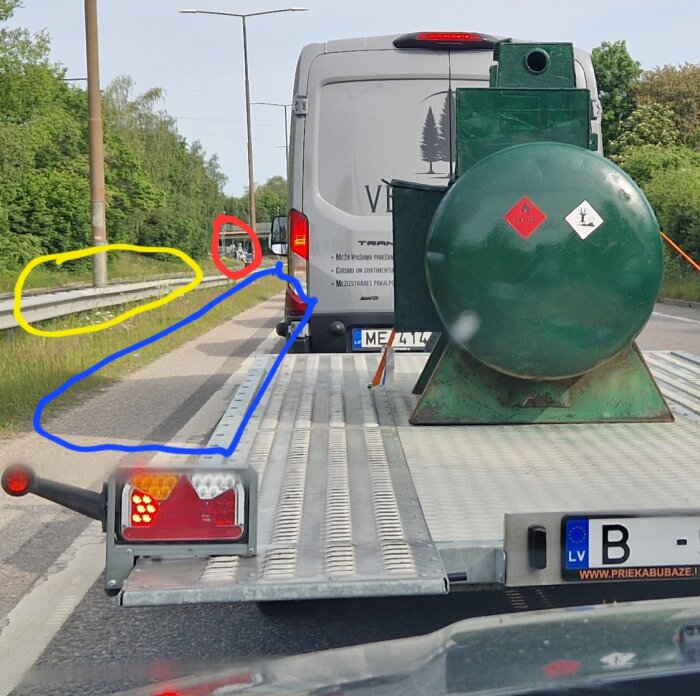Grön tank på släpvagn bakom skåpbil i trafik. Flera bilar i kö. Färgade cirklar markerar detaljer längs vägen, inklusive ett rödljus.
