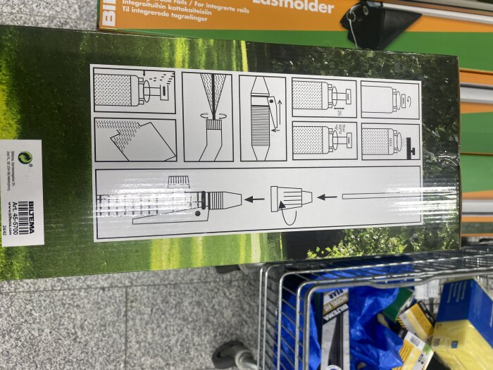 Förpackning för en trädgårdsspruta från Biltema visar instruktioner för justering av munstycket och användning, placerad i en shoppingvagn.
