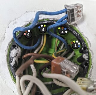 Infälld apparatdosa med kopplingskablar och trådanslutningar, skruvhål och måttangivelser synliga, cc 60 mm mellan skruvarna.