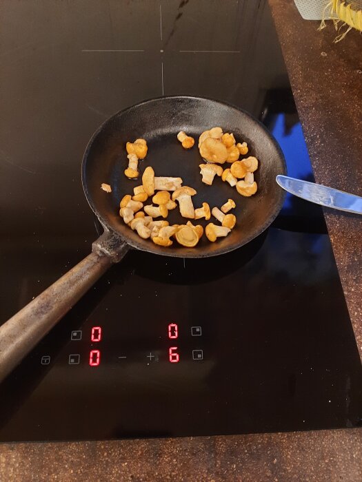Stekpanna med små kantareller på en induktionshäll, redo för tillagning.