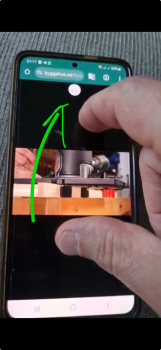 Smartphone-skärm visar en hemsida med en hand som zoomar, en grön pil pekar mot något oväntat element.