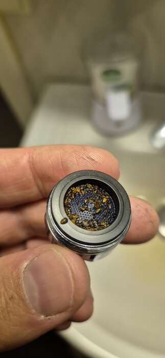 Hand som håller en vattenkrans filter täckt med partiklar i närbild.