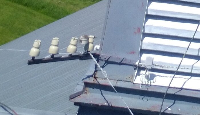 Tak med påhängsisolatorer och telekablar, del av äldre kommunikationssystem; syns från tornet där anslutningar klippts och uppdaterats nyligen.