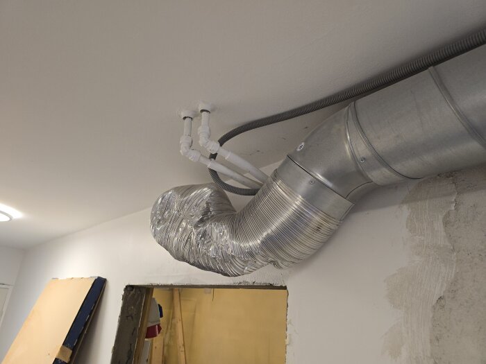 Tilluftsrör och flexrör är omdragna på taket, med anslutning vid husets tilluftsknutpunkt. Öppen vägg visar pågående renovering.