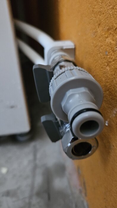 Närbild av en trädgårdsslangskoppling monterad på en ballofixventil i en källare.