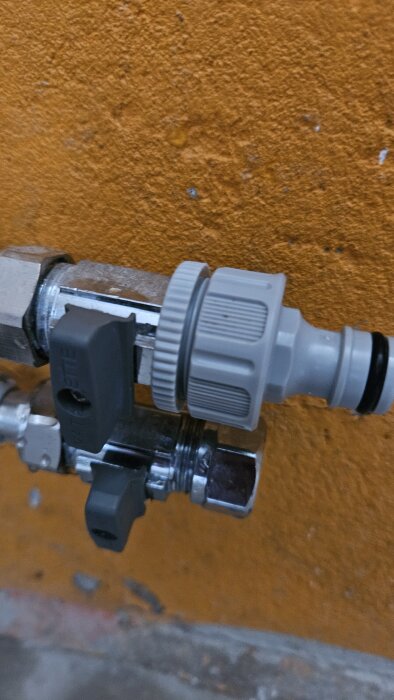 Ballofix med trädgårdsslangskoppling, monterad mot en orange vägg i källaren, där kopplingen blockerar vredet.