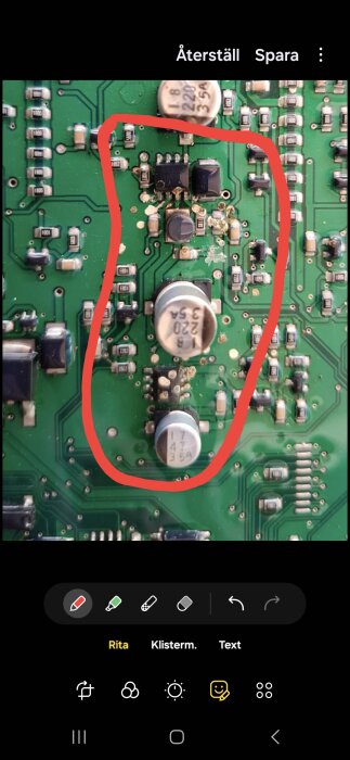 Kretskort med komponenter och två kondensatorer, markerat med en röd cirkel på ett möjligt skadat område.