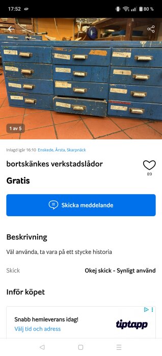 Blå verkstadslådor med flera små lådfronter och etiketter, placerade på ett rött golv i en verkstadsmiljö.