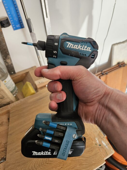 Hand håller en Makita sladdlös borrskruvdragare med flera bits fästa vid basen.