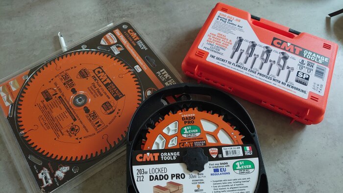 Fintandade sågklingor och ett pluggborrset från CMT Orange Tools placerade på ett bord.