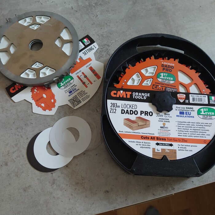 Förpackning med CMT Dado Pro klingor och distansbrickor, inklusive instruktioner och shimsen, på ett bord.