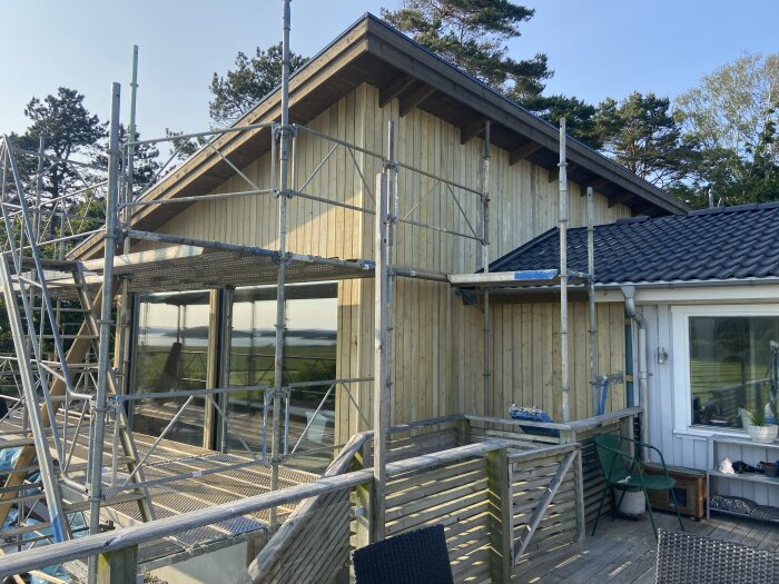 Byggnation av husfasad med ställningar, vissa träbrädor visar missfärgning.