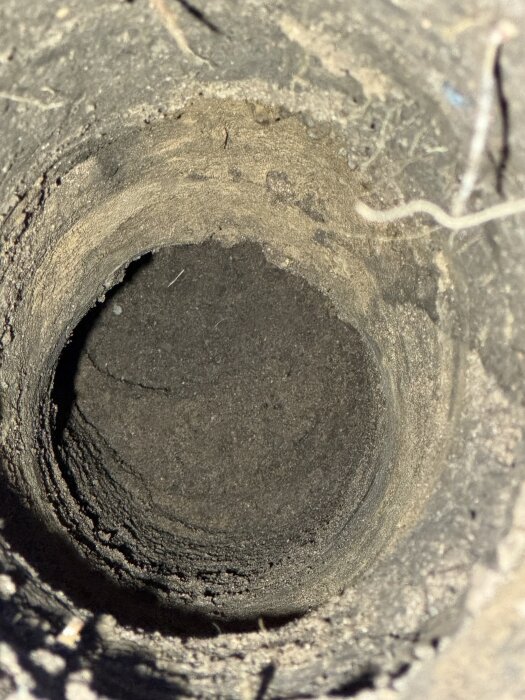 Ett djupt borrhål i marken med synliga lager av jord och sten, föreställande ett projekt där berget stängt av vidare borrning.